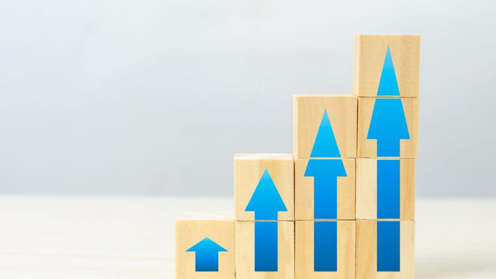 Stacked wooden blocks with ascending blue arrows symbolizing business growth and the importance of working capital for expansion.